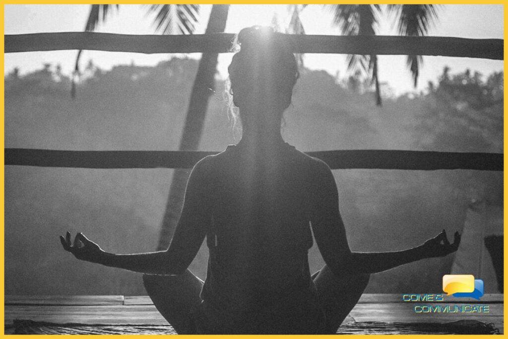 Contraluz de una chica meditando de cara al sol con los codos apoyados sobre sus rodillas